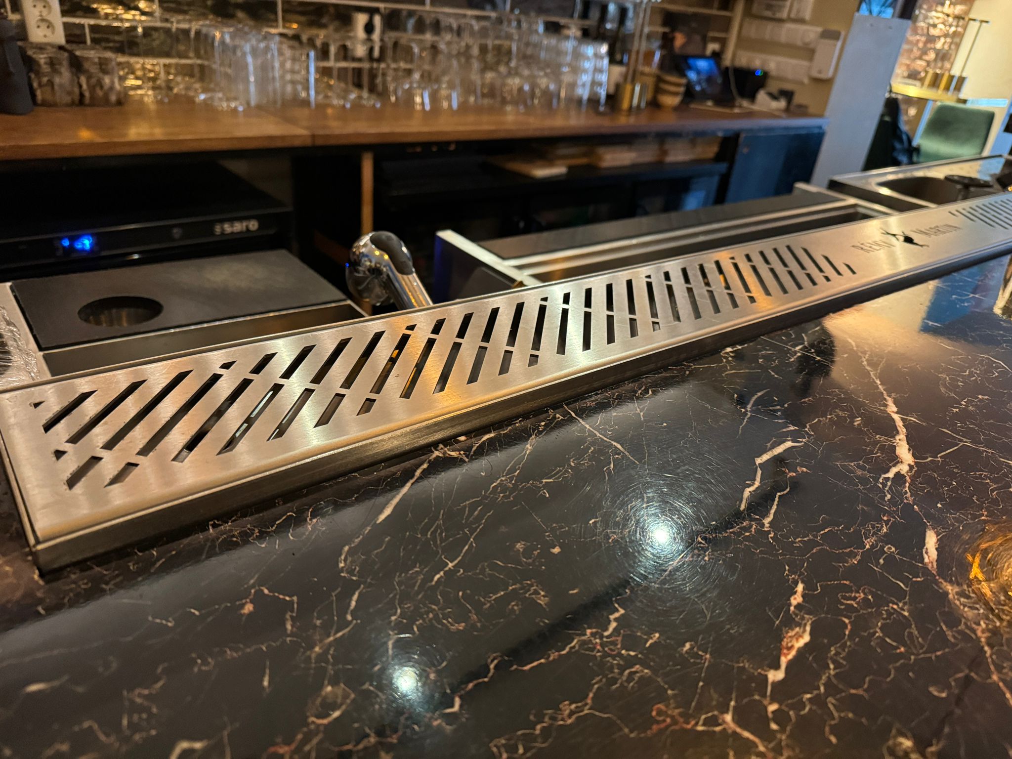 Commercial stainless steel drink rail installed on bar countertop